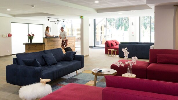 A modern hotel lobby with a reception desk, seating areas, and a view of the outdoors. - Alpine Comfort near Slopes (chamonix mont blanc)