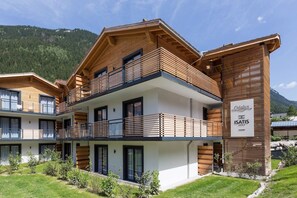 A modern multi-story hotel with wooden balconies and a sign indicating 'ISATIS' accommodation.