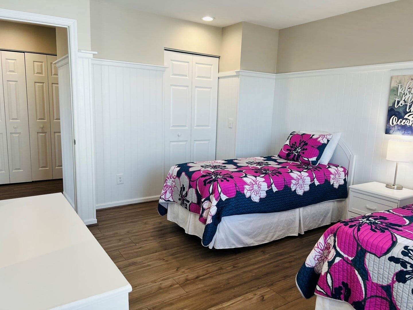 A bedroom with a bed, a nightstand, a dresser, and a closet.