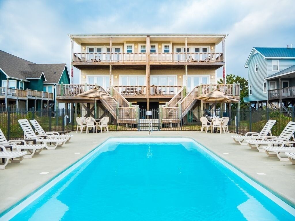A hotel with a pool, outdoor seating, and a multi-story building with balconies.