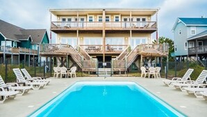 A hotel with a pool, outdoor seating, and a multi-story building with balconies.