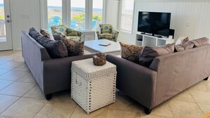 Ein Wohnzimmer mit zwei Sofas, einem Couchtisch, einem Fernseher und einem großen Fenster mit Blick.