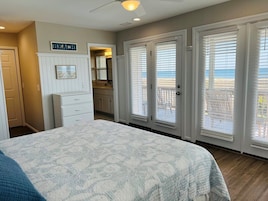 Un dormitorio con cama, cómoda, espejo y puerta que da a un balcón con vistas.