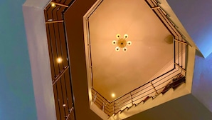 A geometric, multi-level interior with a central light fixture and metal railings. - Angel Hospitality Services (Lagos)