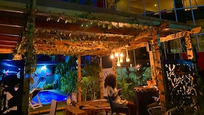 An outdoor seating area with wooden furniture and a pool. - Angel Hospitality Services (Lagos)
