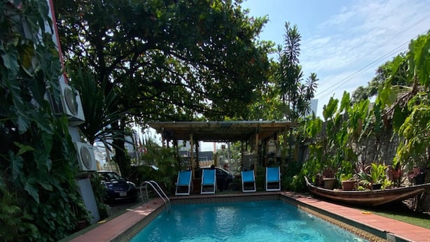 A poolside table with a plate of food, a pool, and lounge chairs in the background. - Angel Hospitality Services (Lagos)