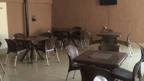 Une pièce comprenant plusieurs tables et chaises, un téléviseur à écran plat fixé au mur et une porte bien visible.