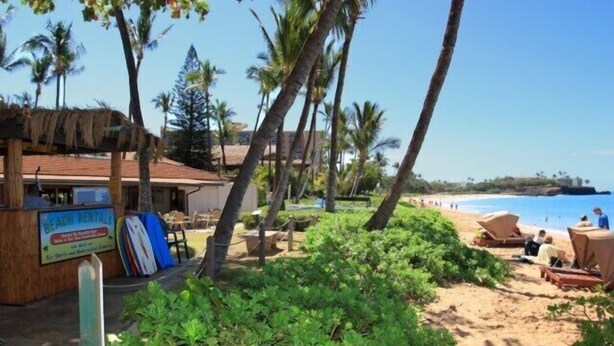 A beach rental area with a sign, palm trees, and beach chairs. - Maui Kaanapali S #b133 Studio Bedroom Condo by RedAwning (Lahaina)