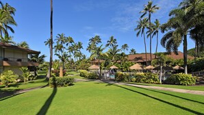A resort with a well-maintained lawn, palm trees, and thatched-roof structures. - Maui Kaanapali S #b133 Studio Bedroom Condo by RedAwning (Lahaina)
