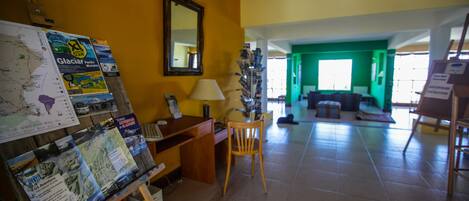 Una habitación con un escritorio de madera, una silla, un mapa en la pared y un fondo de pared verde.