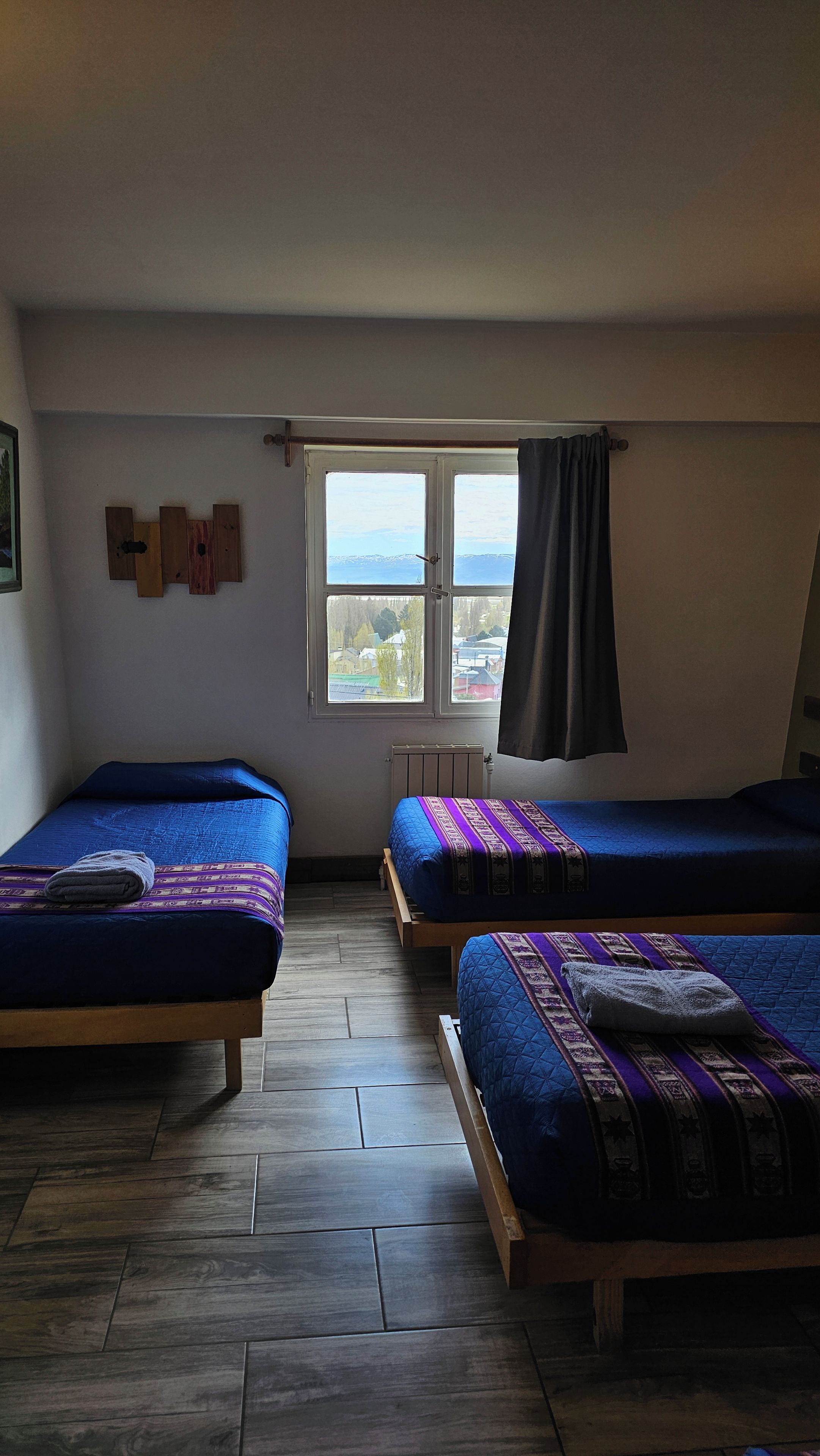 Un dormitorio con dos camas, un ventanal con vistas y un radiador.