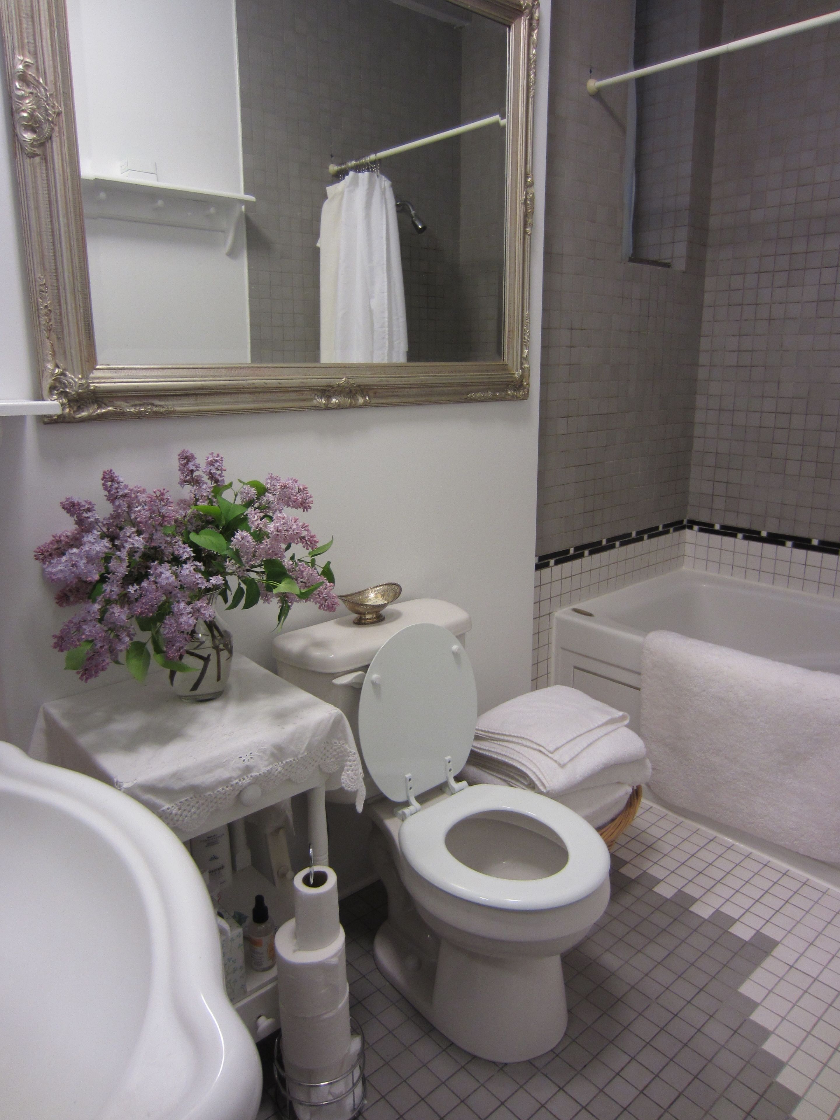 A bathroom with a toilet, sink, mirror, and bathtub.