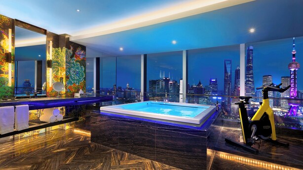 A modern hotel room with a large window, a swimming pool, and an exercise bike.