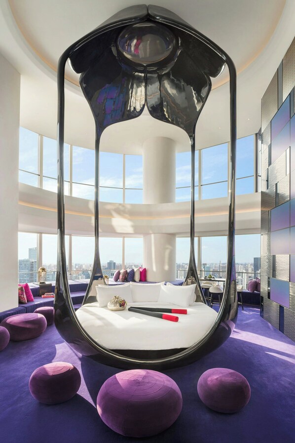 A modern room with a unique spherical bed design, large windows offering a city view, and purple accents. - W Shanghai - The Bund (Shanghai)