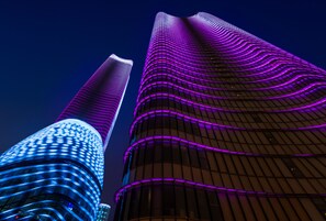 Two high-rise buildings with distinctive architectural designs and illuminated facades. - W Shanghai - The Bund (Shanghai)