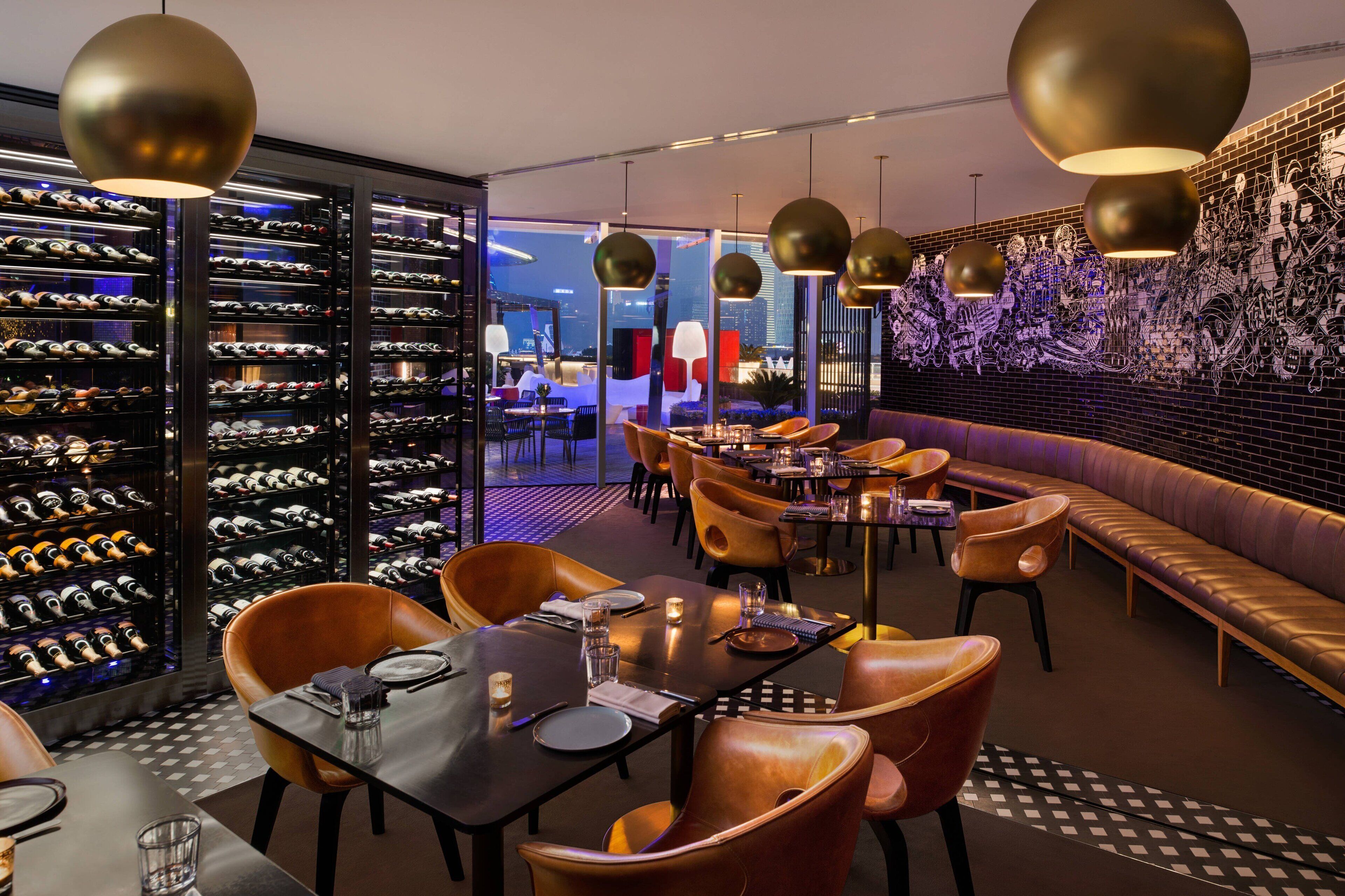 A modern restaurant with leather seating, a wine cellar, and a city view.