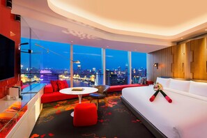 A modern hotel room with a large city view, a sofa, a bed, and a small table. - W Shanghai - The Bund (Shanghai)