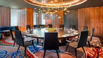 A modern conference room with a round table, black chairs, and a unique ceiling light fixture.