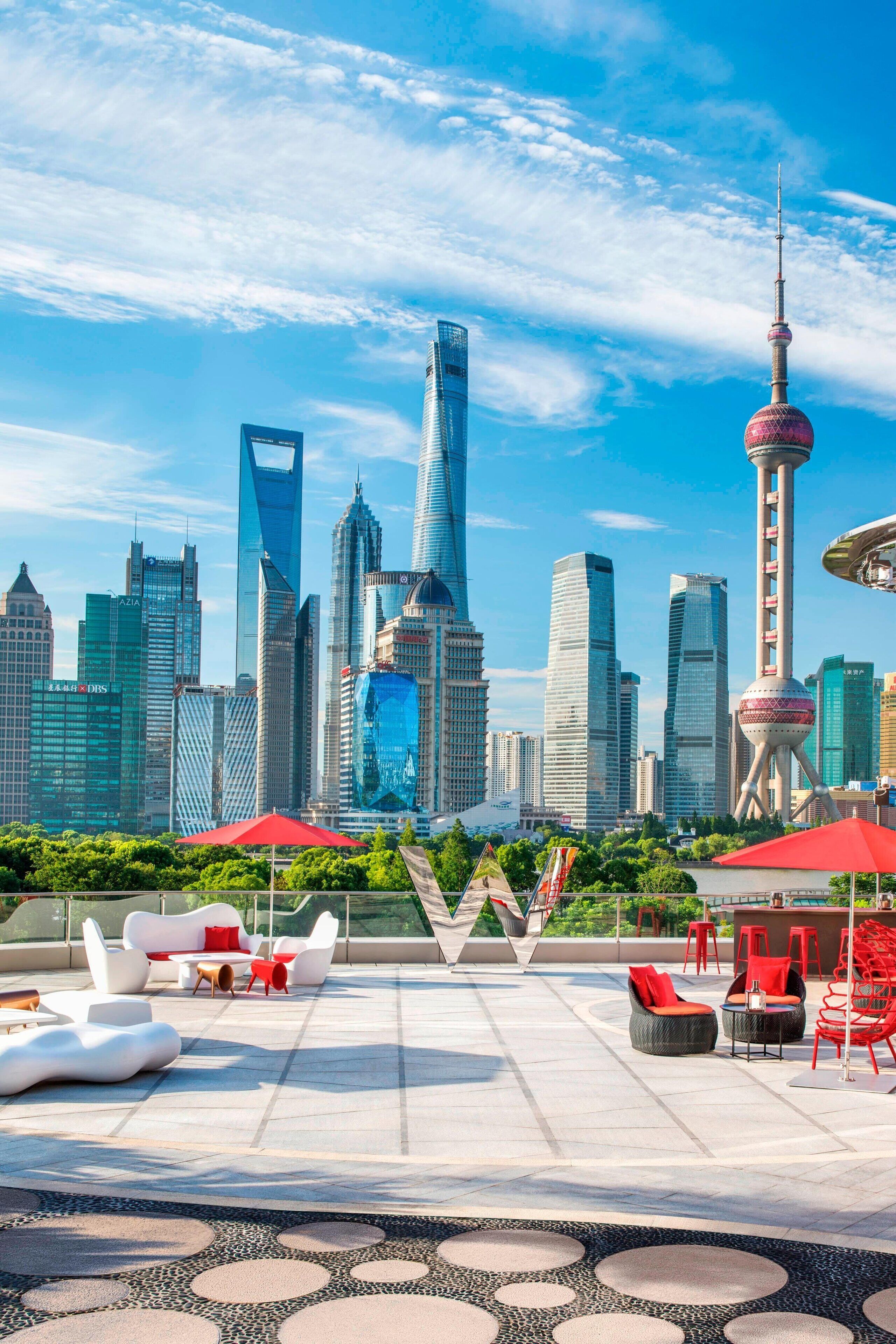 Un salón en la azotea con asientos modernos, vistas del horizonte de la ciudad y la Torre Perla Oriental.