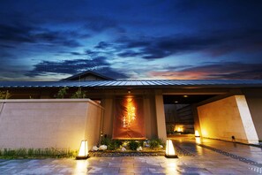 A modern building with a large illuminated banner, a paved entrance, and a well-maintained garden area.