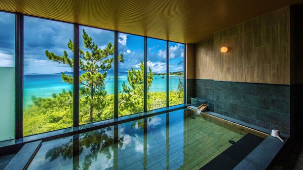 A modern interior with large windows offering a view of a turquoise sea and green landscape. - Umino Ryotei Okinawa Nakamasou (Onna)