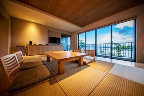 A modern room with a wooden dining table, tatami mats, and a view of the outdoors. - Umino Ryotei Okinawa Nakamasou (Onna)