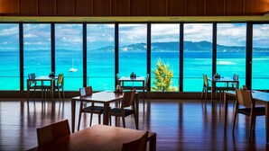 A dining area with large windows overlooking a turquoise sea and distant mountains. - Umino Ryotei Okinawa Nakamasou (Onna)