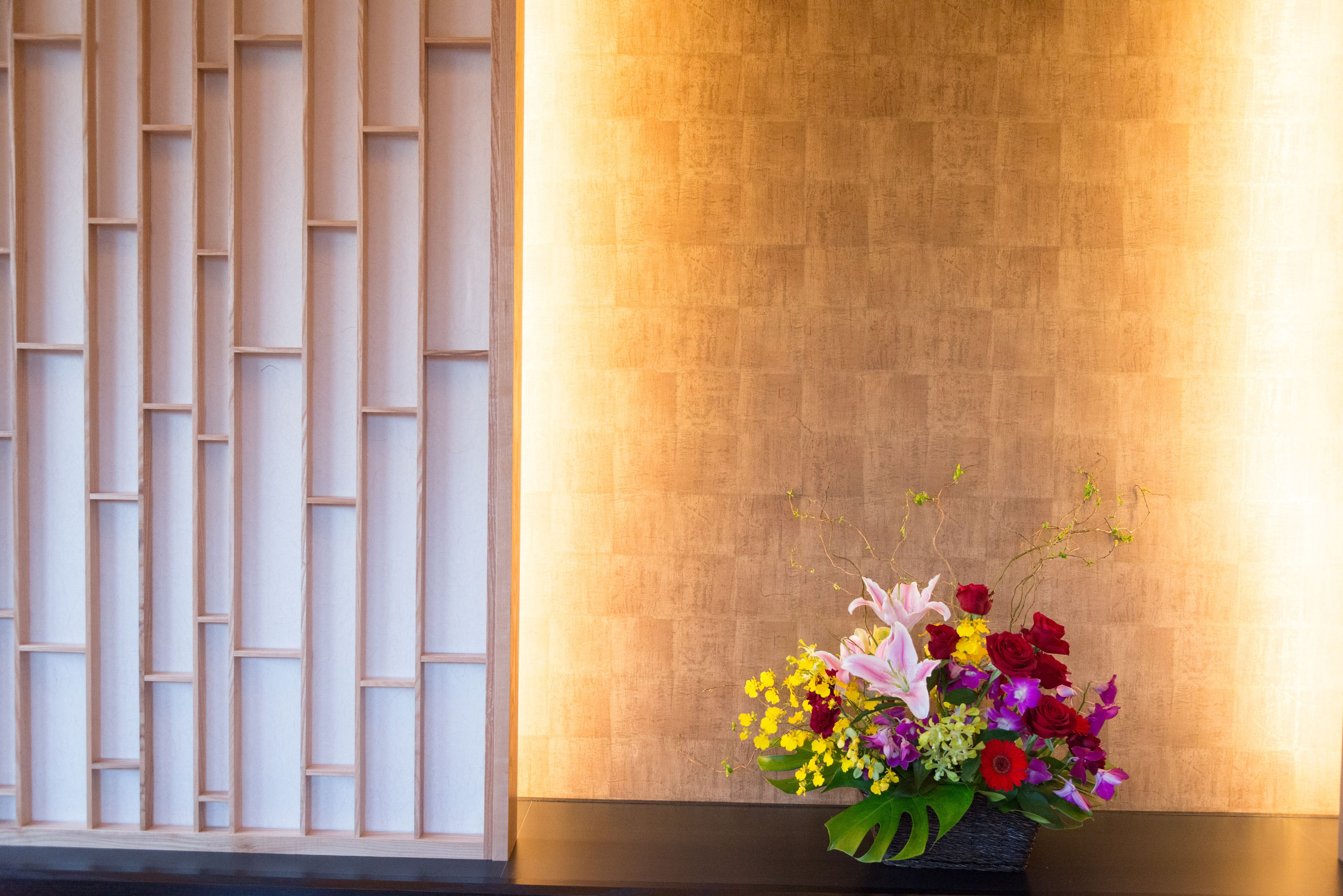 A wall with a geometric pattern and a floral arrangement.
