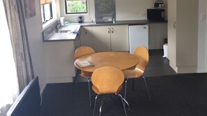 Una cocina compacta con comedor, microondas, radio y una ventana con persianas.