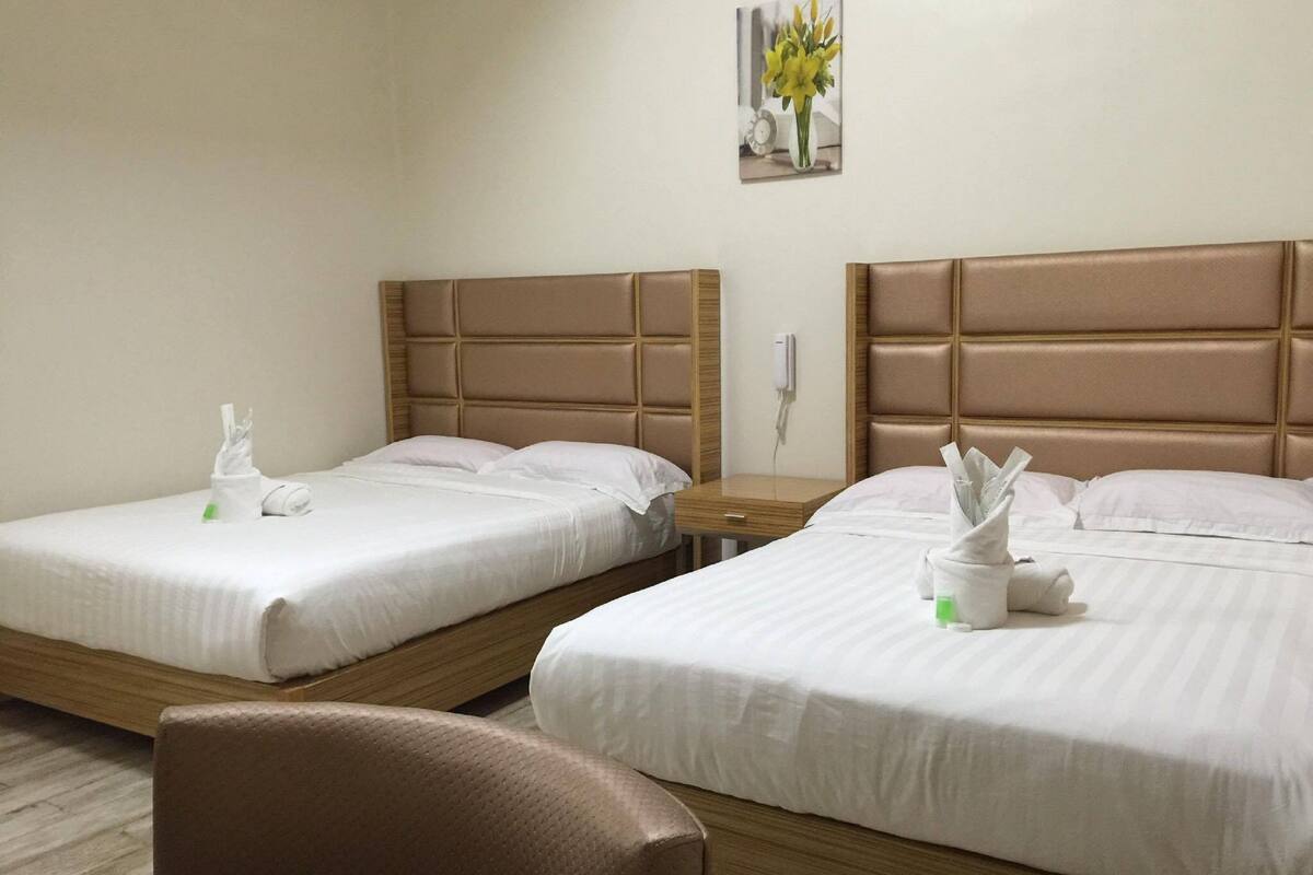 Two single beds with wooden headboards, white linens, and a small bedside table with a lamp.