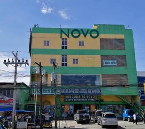 A multi-story building with the name "NOVO" prominently displayed. It features a sign for "MEJO HOTEL" on the second floor and a "WELCOME TO NOVO" sign at the ground level. There is a visible entrance with a ramp leading up to the main doors. - Meaco Hotel - Solano (Solano)