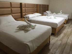 Une chambre d’hôtel avec trois lits, chacun agrémenté de linge de lit blanc et d’une décoration en forme de cygne.