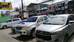 A row of parked cars on a city street with buildings and shops in the background. - Meaco Hotel - Solano (Solano)