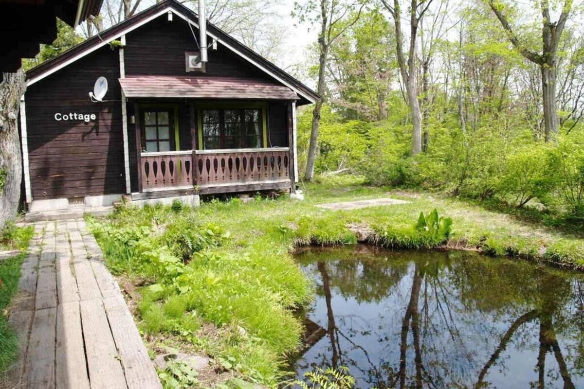 A rustic cabin labeled 'Cottage' with a wooden deck leading to a pond, surrounded by lush greenery.