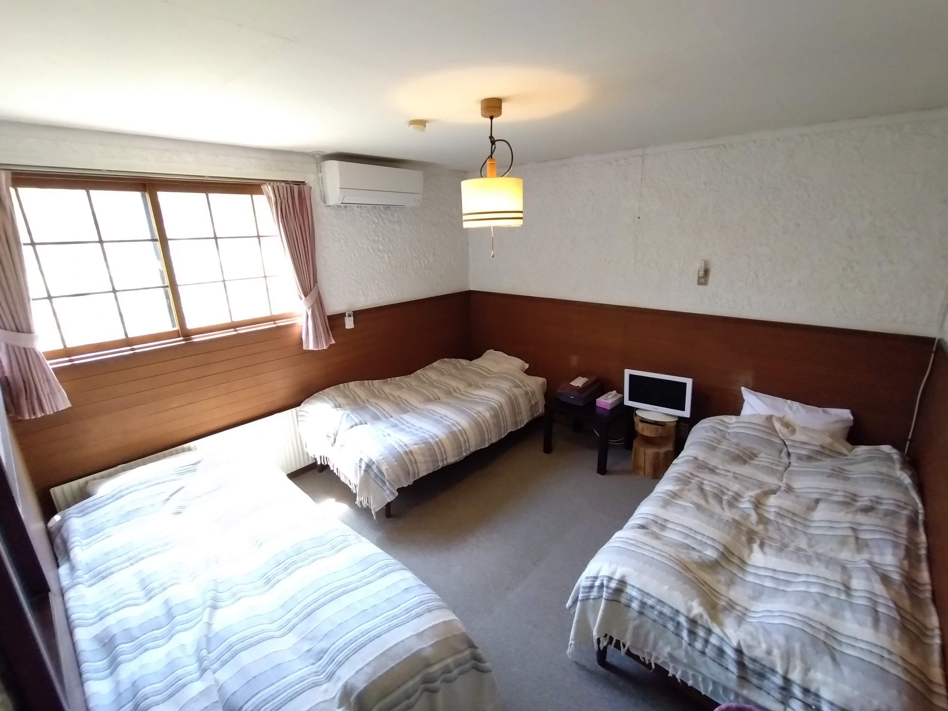 A room with two beds, a television, and an air conditioning unit.