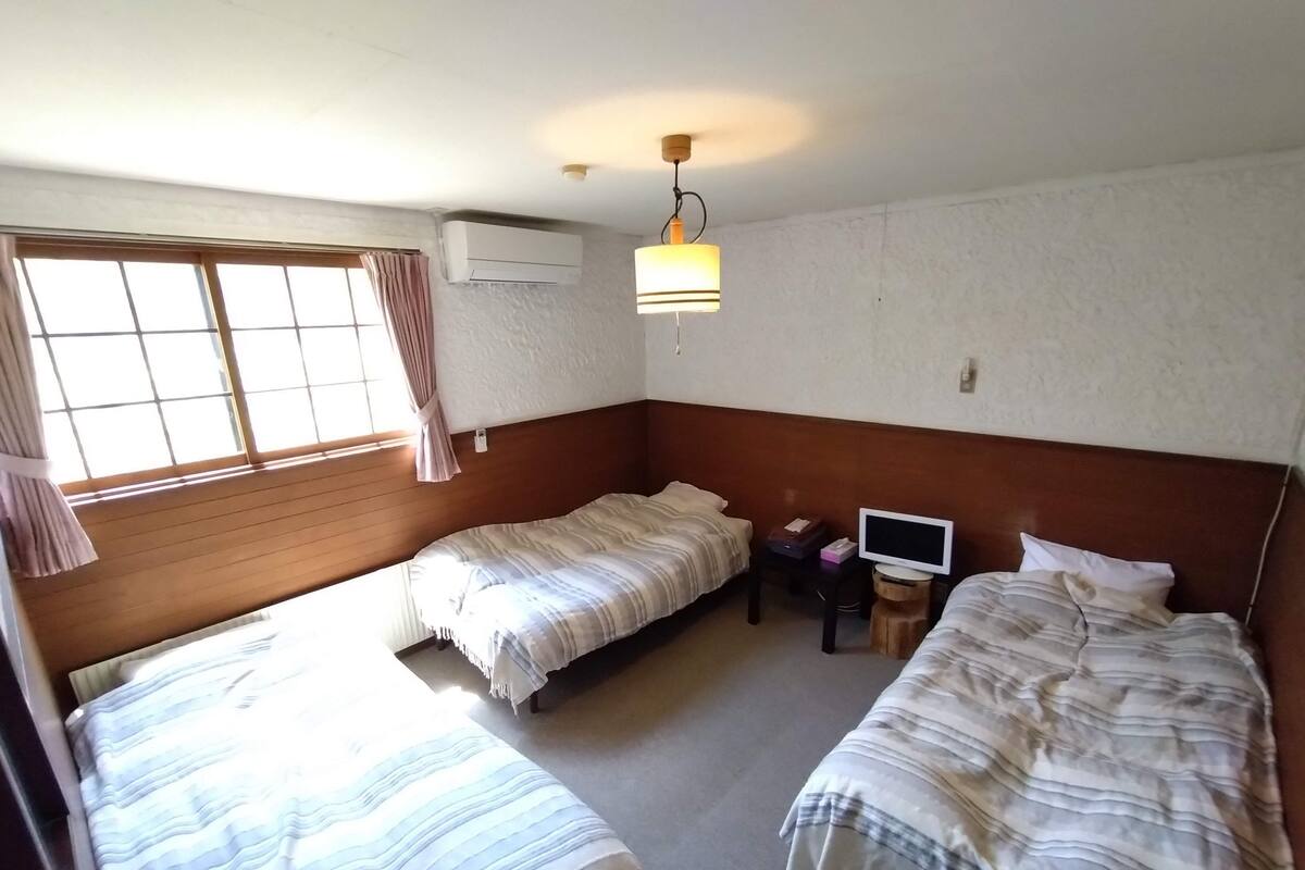 A room with two beds, a television, and an air conditioning unit.