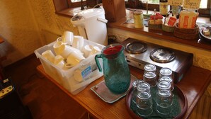 Una encimera de cocina con una cafetera, un envase de leche, una jarra y varios vasos.