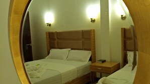 A bedroom with a wooden headboard, a bedside table, and a mirror. - Meaco Hotel - Anilao (Mabini)