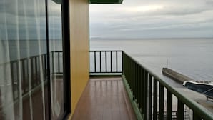 A balcony with a view of the sea, a wooden floor, and a green railing. - Meaco Hotel - Anilao (Mabini)