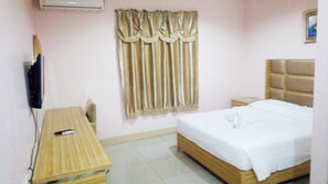 A small hotel room with a single bed, a bedside table, a chair, a TV, and a window with curtains. - Meaco Hotel Legazpi (Legazpi)