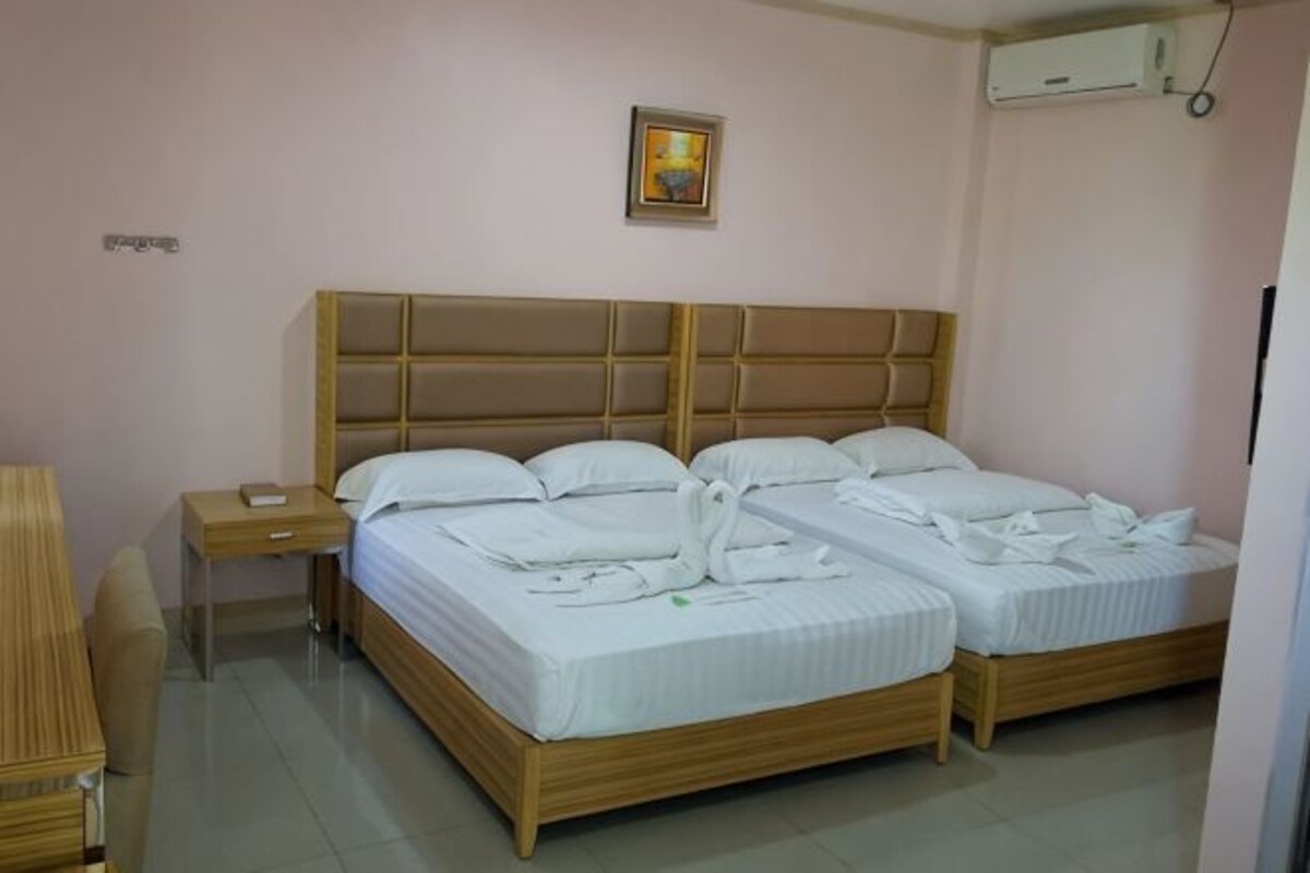 A double bed with a wooden headboard, a bedside table, and a desk with a chair.