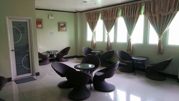 A room with a door, several chairs, a small table, and a window with curtains. - Meaco Hotel Legazpi (Legazpi)