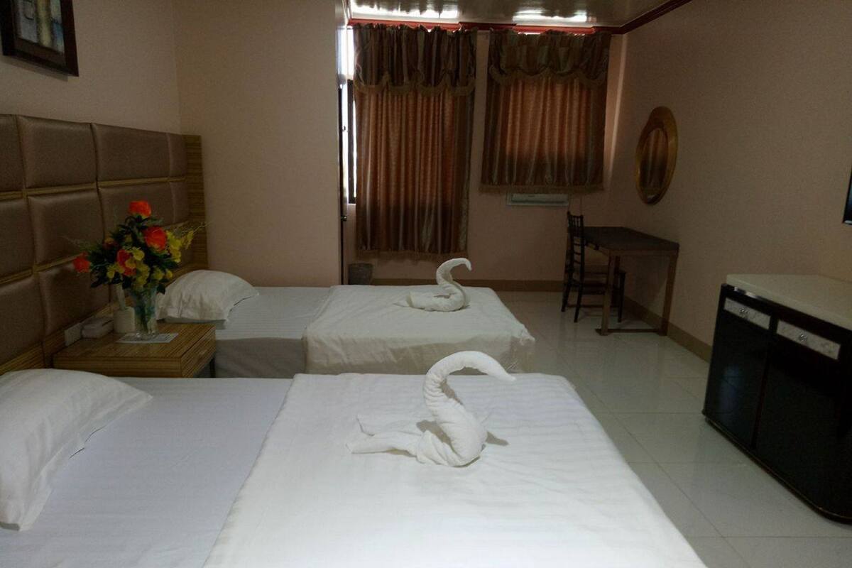 Una habitación de hotel con dos camas, un escritorio, una silla y un televisor.