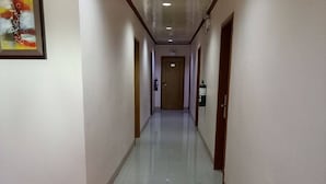 Un pasillo largo y estrecho con pisos de baldosas blancas y puertas de madera a ambos lados.