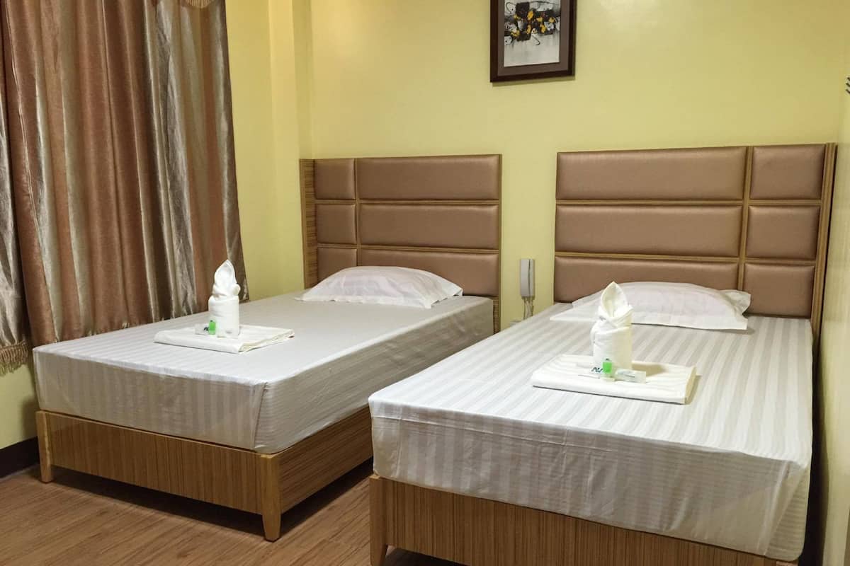 Two single beds with headboards, wooden floors, and a framed picture on the wall.