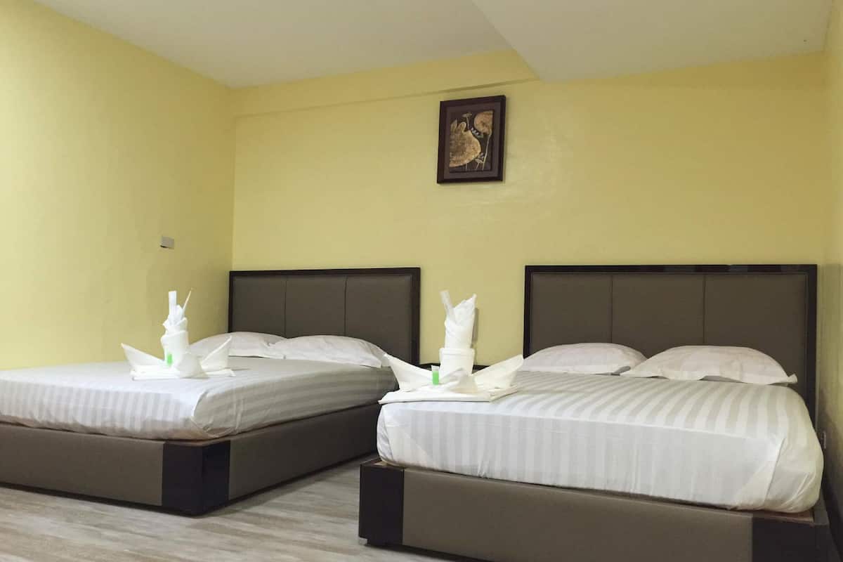 Two single beds with headboards, a small framed picture on the wall, and a plain yellow wall.