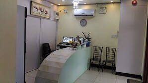 Un espace d’accueil avec un comptoir incurvé, un ordinateur, une horloge et deux chaises.