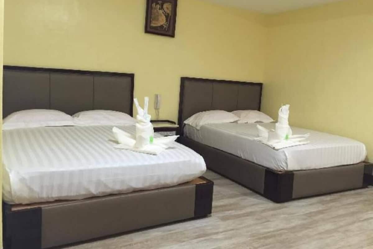 Two twin beds with white linens and towels, a bedside table, and a framed picture on the wall.