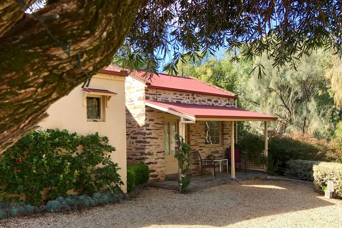 Una casa de piedra con techo rojo y porche cubierto.