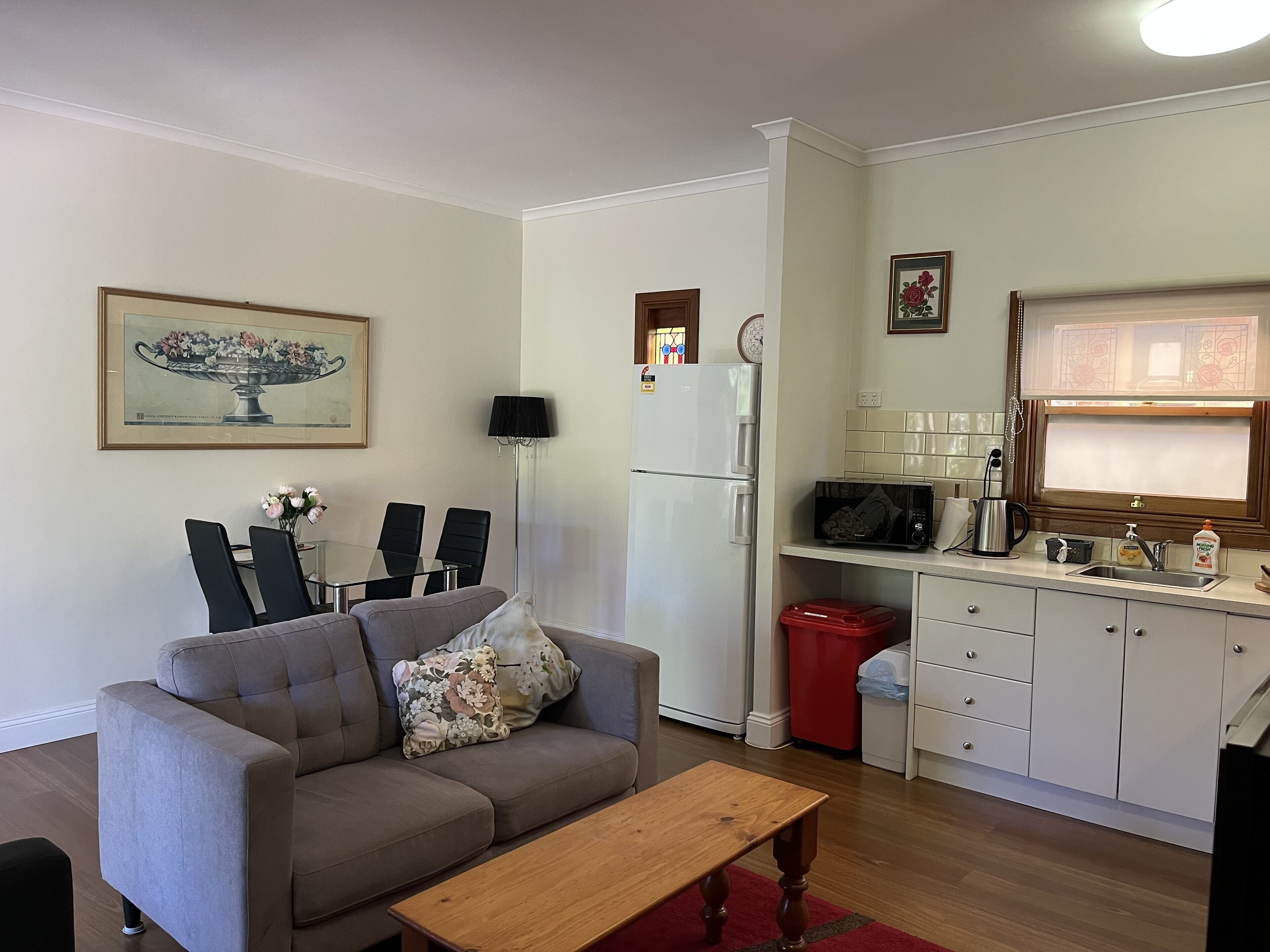 Un espacio habitable compacto con sofá, mesa de comedor, cocina que incluye microondas, refrigerador y armarios.